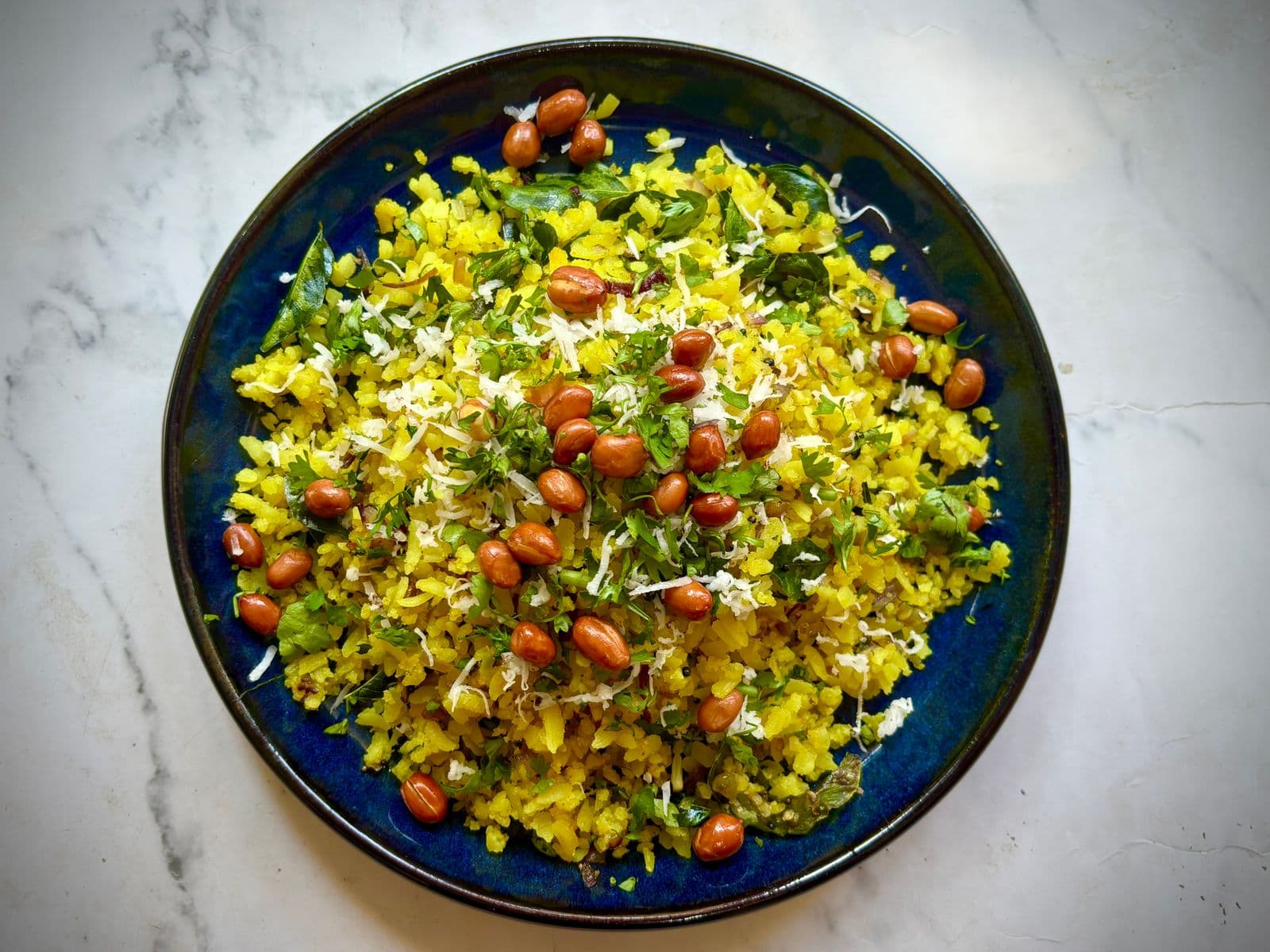 A bowl of poha with peanuts, coconut and coriander